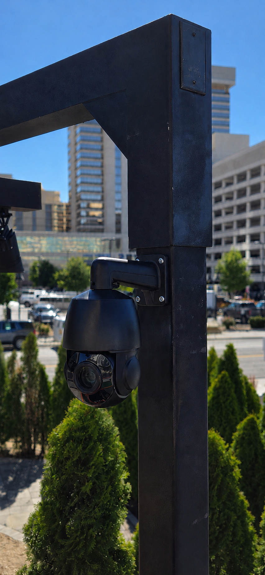 Discreet black AI camera mounted to a steel post near an architectural lighting installation in downtown Reno.