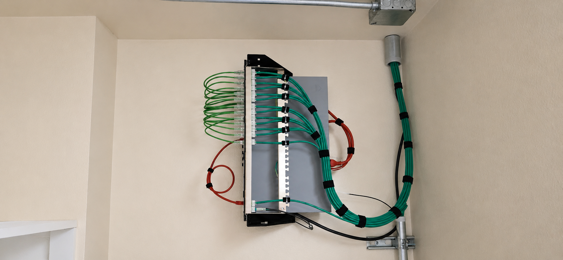 Wall-mounted hotel IDF with neatly routed green network cabling supporting 13 wireless access points.