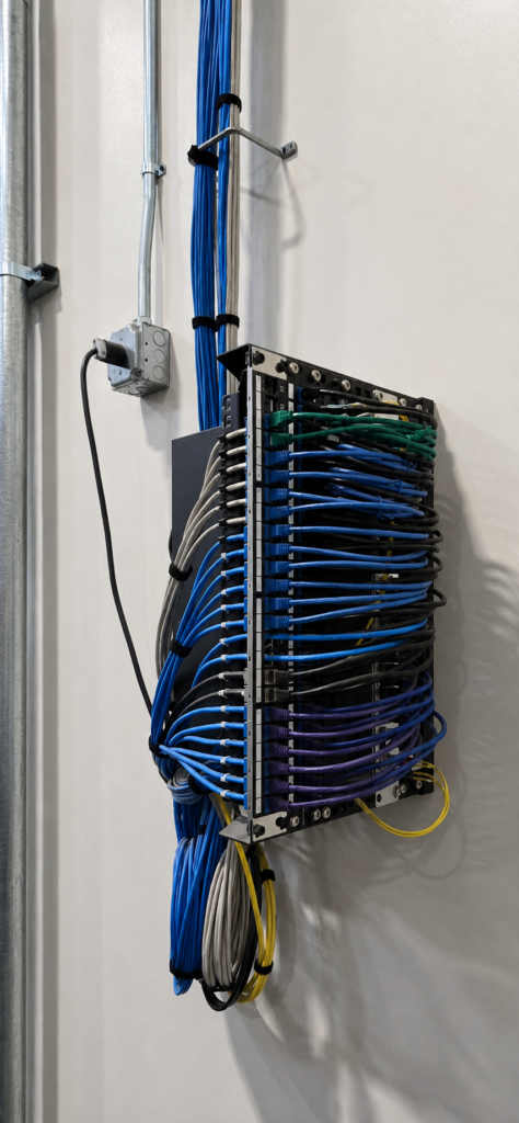 Side view of a warehouse IDF with accessible patch panels, neatly secured cabling, and network switches positioned toward the rear.