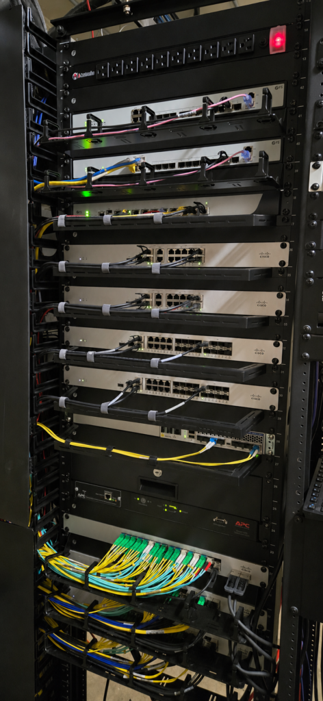 Network rack containing security appliances, switches, fiber connections, and power equipment.