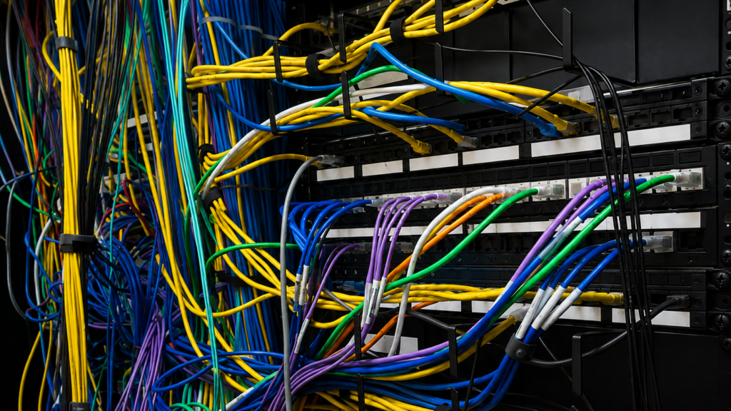 Dense multicolored network cabling obscuring equipment in a communications rack.