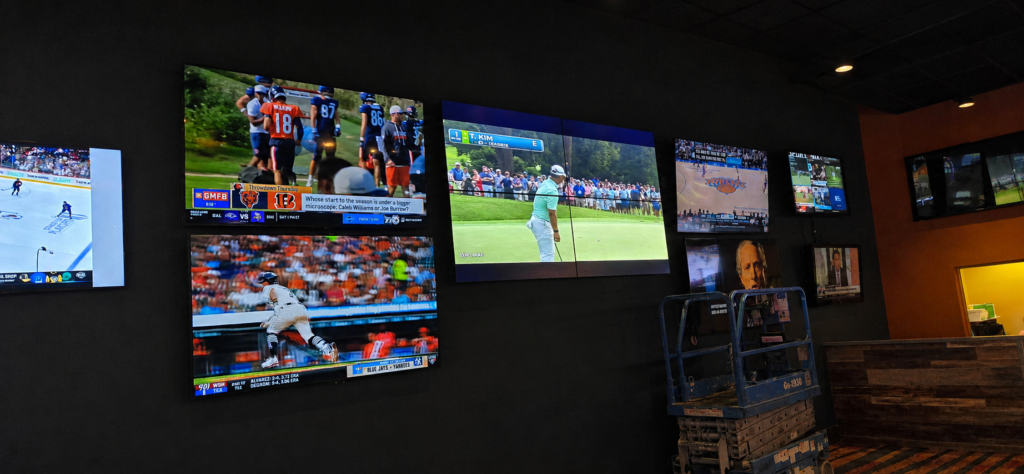 Multiple televisions showing sports programming across the wall of a sportsbook.