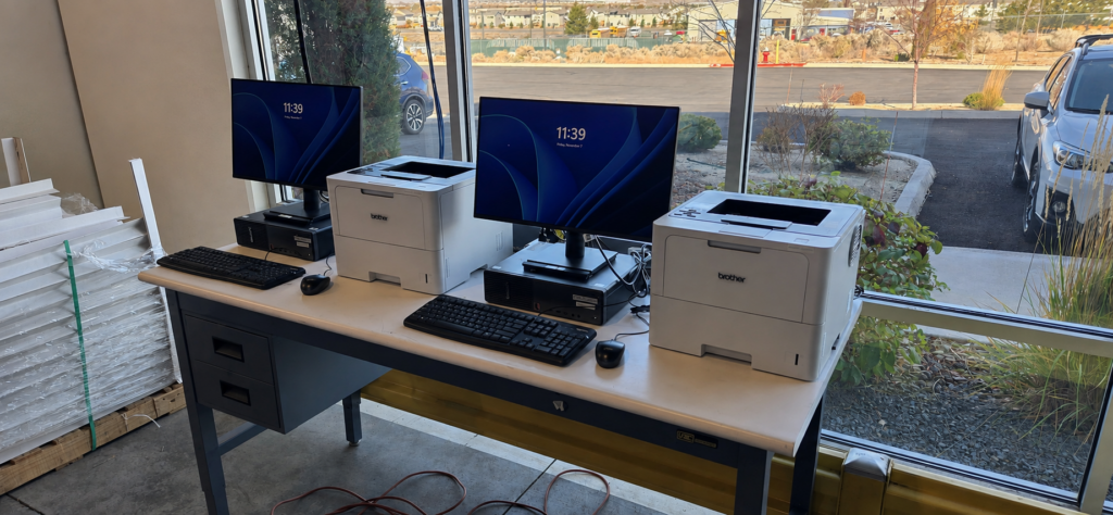 Two newly installed computer workstations with Brother monochrome laser printers on a shared workbench.