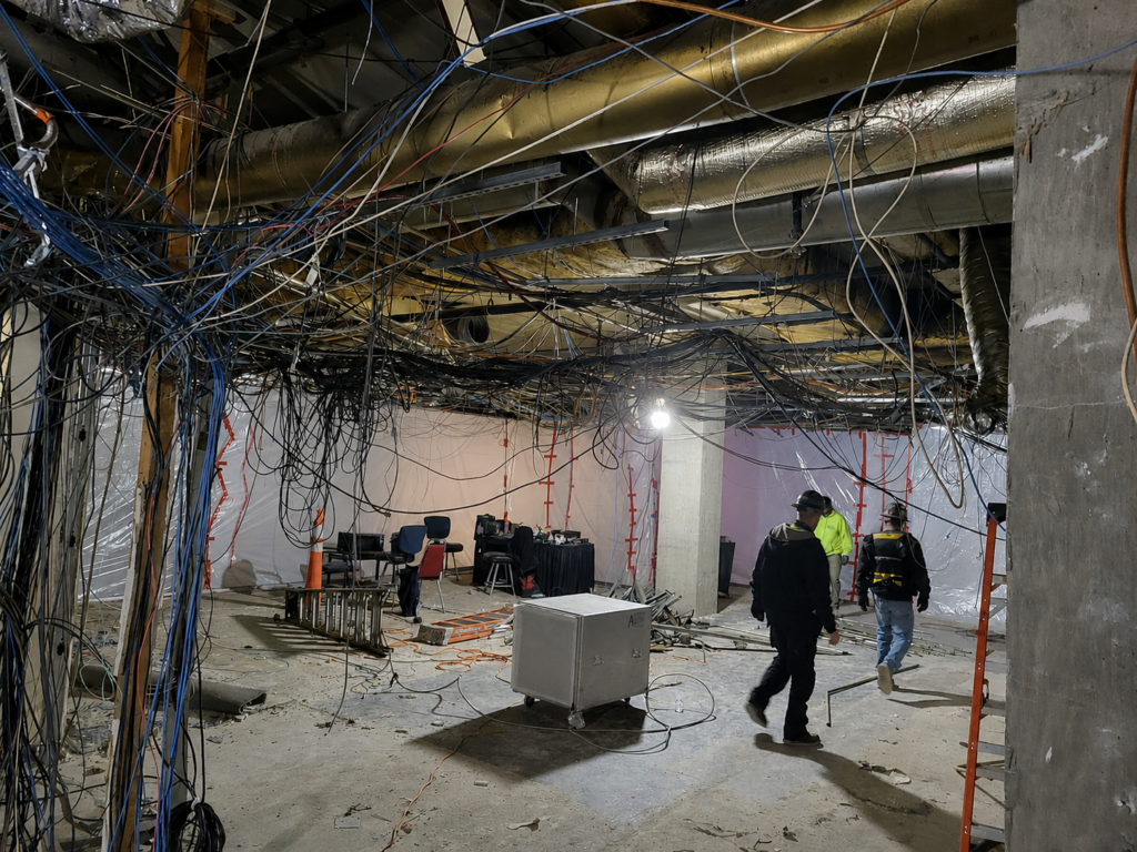 Surveillance-room renovation exposing decades of abandoned cabling above the ceiling before removal and replacement.